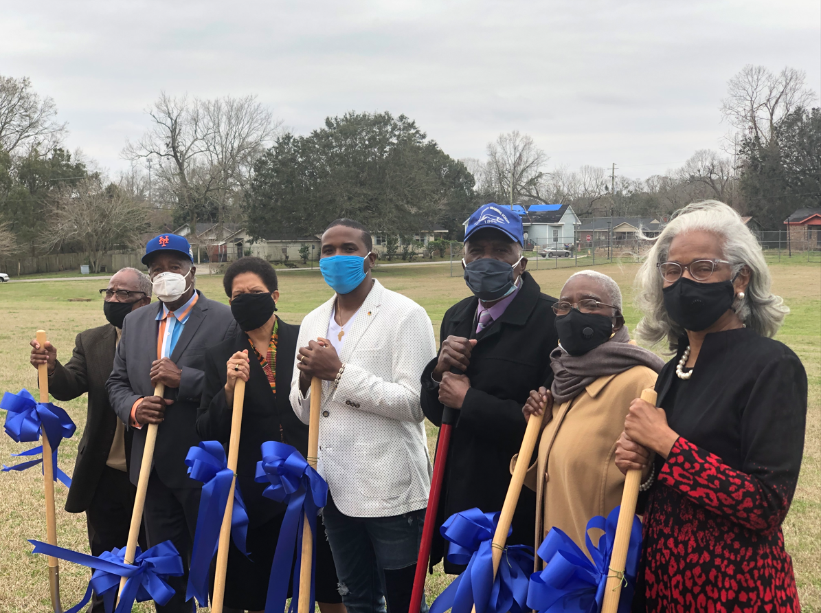 Community leaders holding blue-ribboned shovels at the Heritage House groundbreaking ceremony