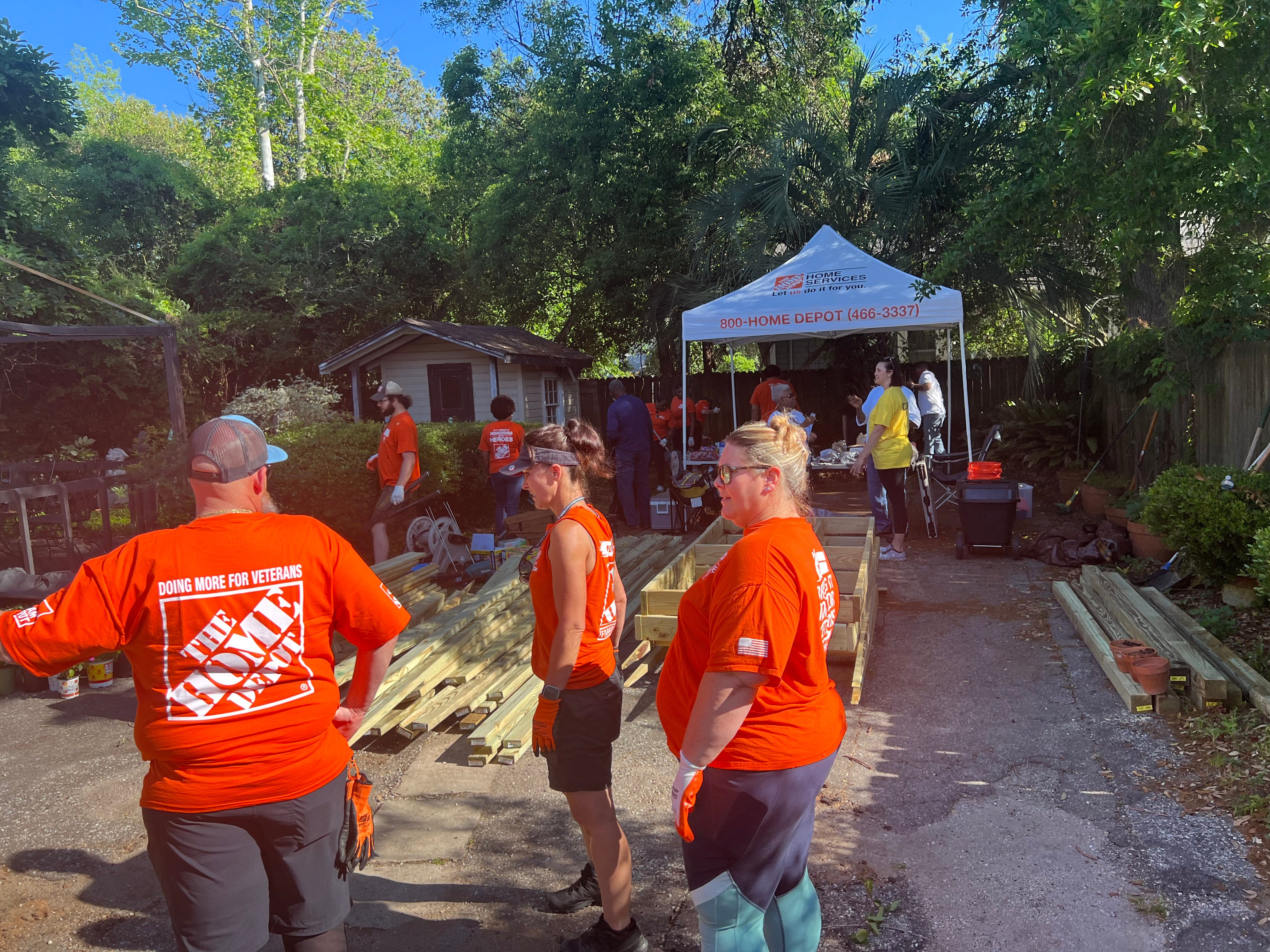 Home Depot volunteers building raised garden beds under the Home Depot Home Services tent