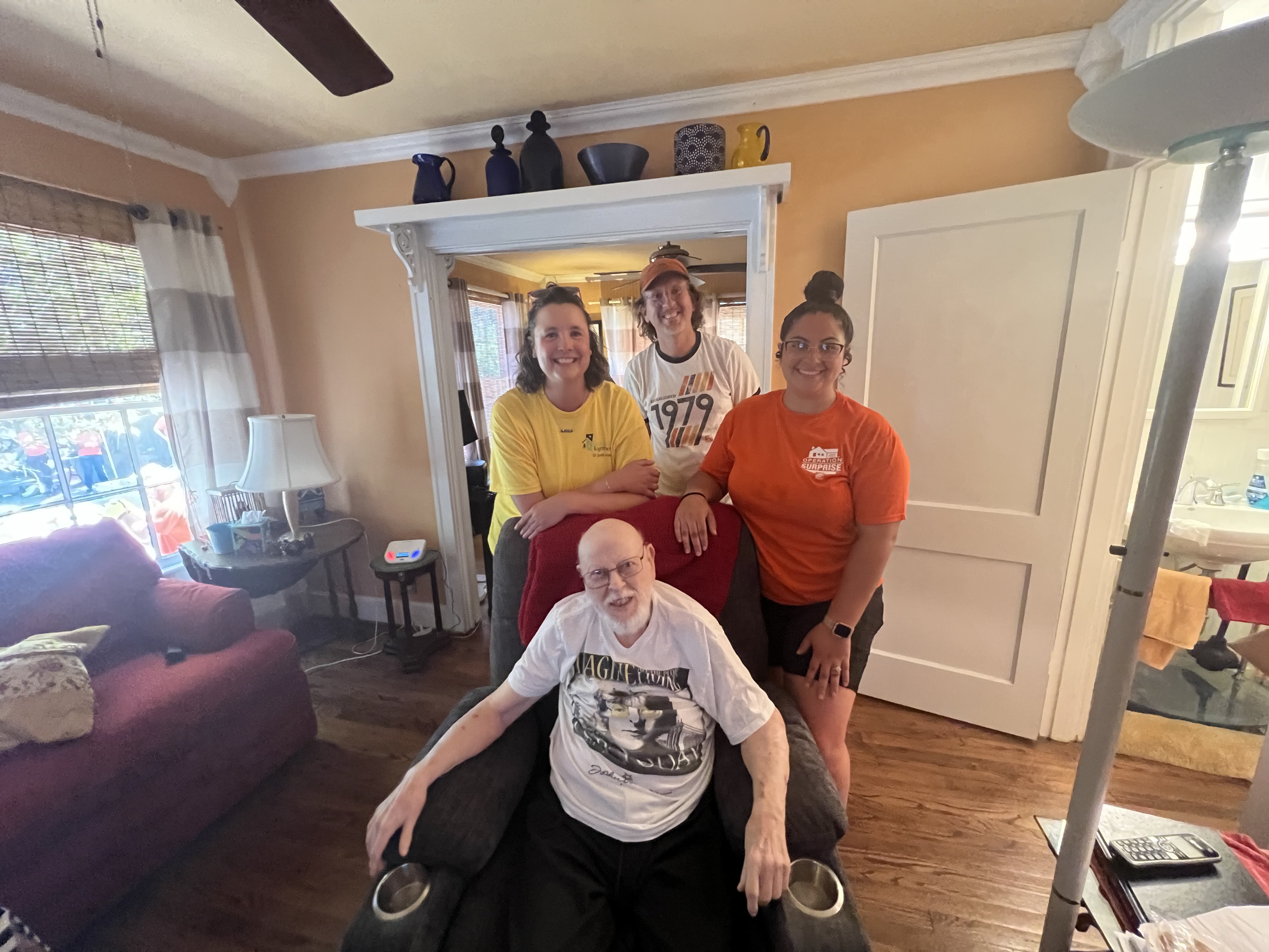 Volunteers gathered with an elderly veteran homeowner inside his living room